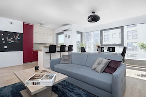 Ein modernes Wohnzimmer mit grauem Sofa, einem Couchtisch und einem Essbereich mit Glastisch und Stühlen.
