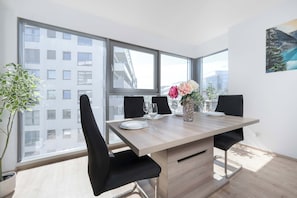 Ein stilvolles Esszimmer mit einem Holztisch, schwarzen Stühlen und einer Blumenvase.