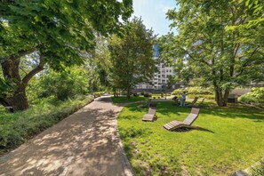 Ein Weg, der durch einen Park mit Bänken und Bäumen führt.