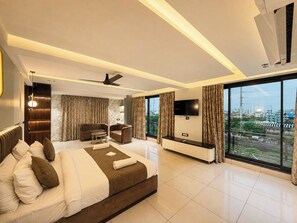 A modern hotel room with a large bed, a seating area, a flat-screen TV, and a city view. - HOTEL ROYAL GANGA (Patna)