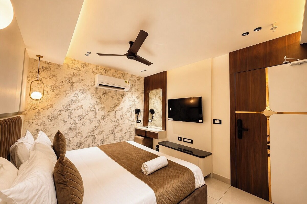 A hotel room with a bed, a desk, a TV, a wardrobe, and a ceiling fan.