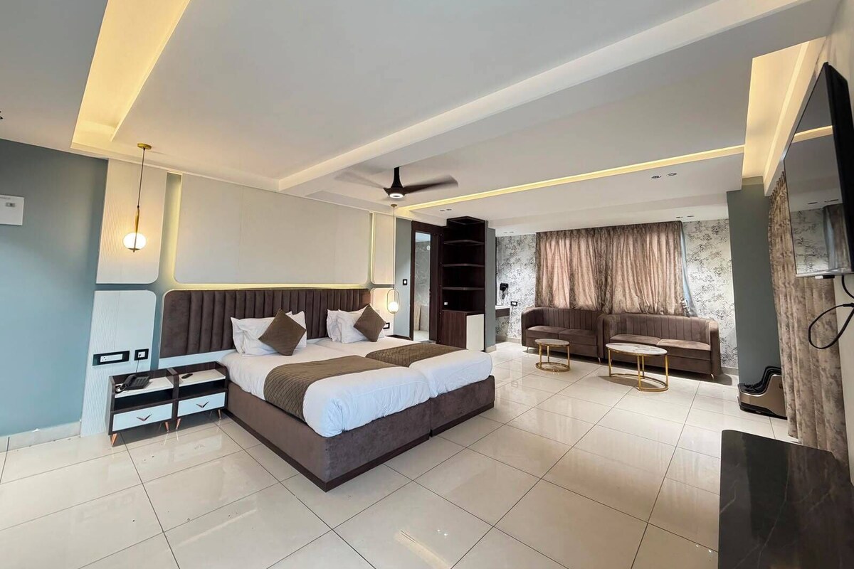 A modern bedroom with a large bed, a sofa, a TV, and a ceiling fan.