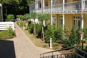 A multi-story building with a paved pathway leading to a white fence. - Holiday apartment Dünenschloss 319669 (Kühlungsborn)