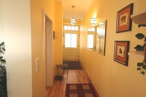 A hallway with a wooden floor, a door at the end, and a wall-mounted light fixture. - Holiday apartment Dünenschloss 319669 (Kühlungsborn)