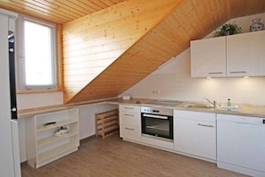 Eine Küche mit weißen Schränken, einem Backofen und einem Fenster.