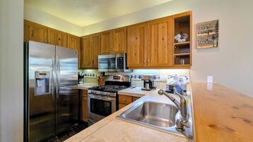 Una cocina con armarios de madera, electrodomésticos de acero inoxidable, microondas integrado y un lavabo.