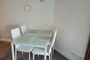 A dining area with a white table and chairs, a heart-shaped decoration on the wall, and a power outlet. - Holiday apartment Strandstraße 42 322219 (Kühlungsborn)