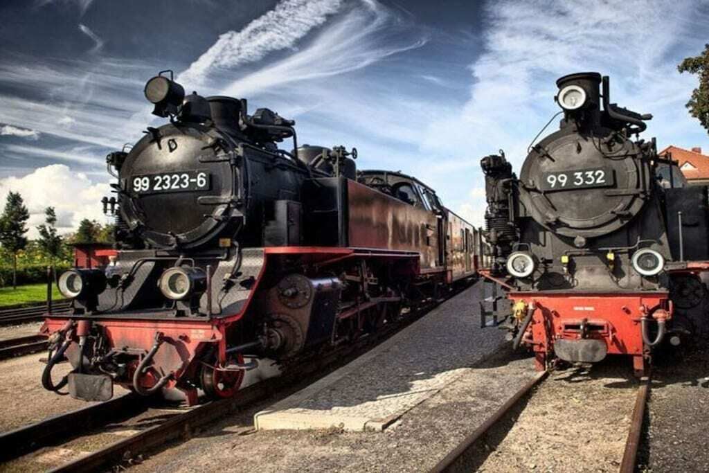 Two steam locomotives numbered 99 2323-6 and 99 332 on parallel tracks.