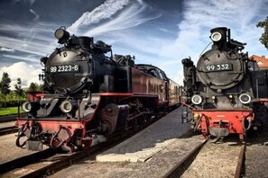 Due locomotive a vapore con i numeri 99 2323-6 e 99 332 su binari paralleli.