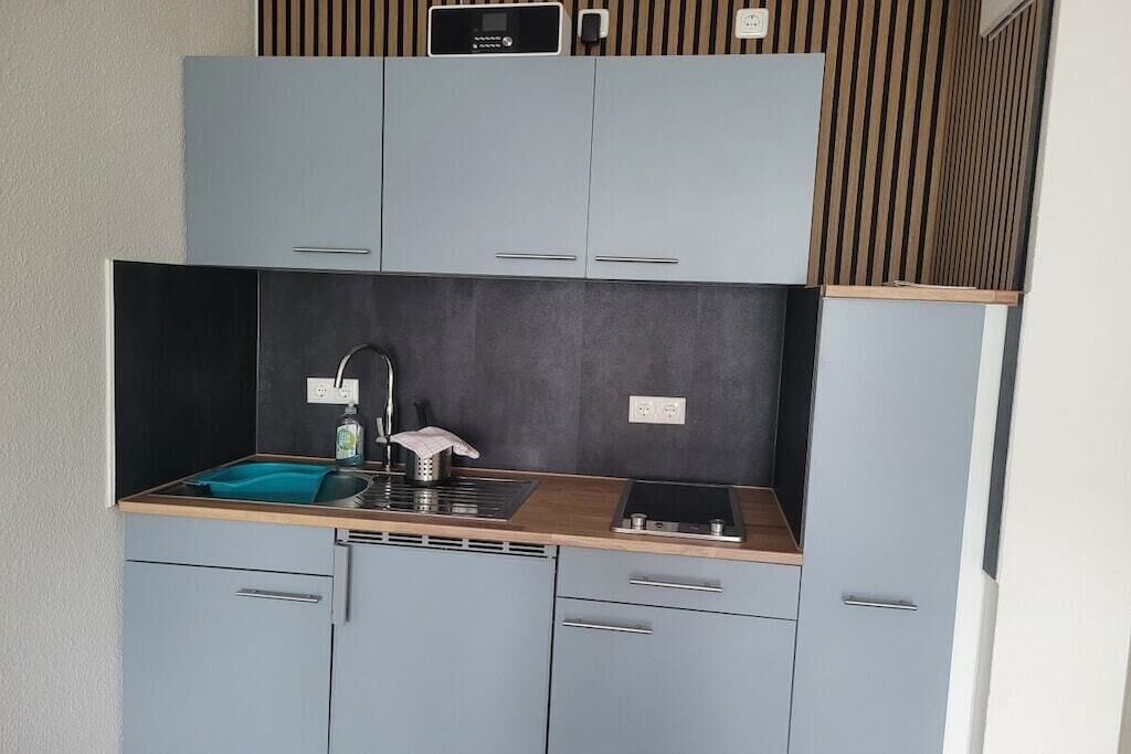 Eine kleine Küche mit integriertem Herd, Spüle und einer Holz Arbeitsplatte.