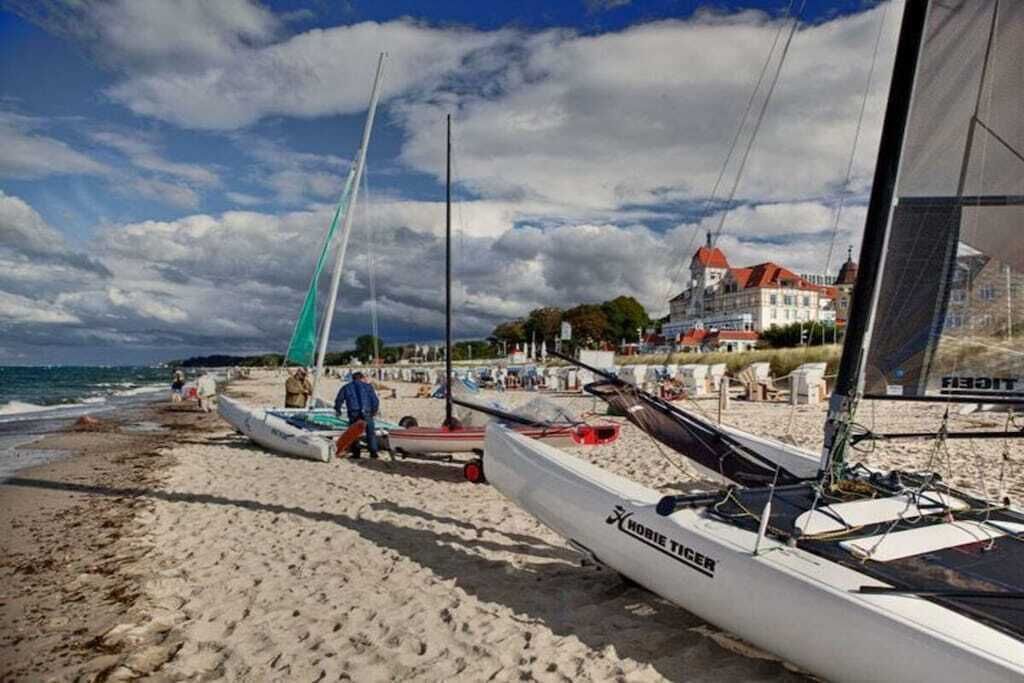 A beach with sailboats, a sandy shore, and a building in the background.