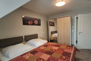 Ein Schlafzimmer mit einem Bett, einem Nachttisch, einem Spiegel und einer Tür.