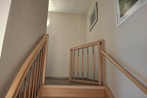 Eine Holztreppe mit Glastrennwand, die zu einer Zwischenebene führt.