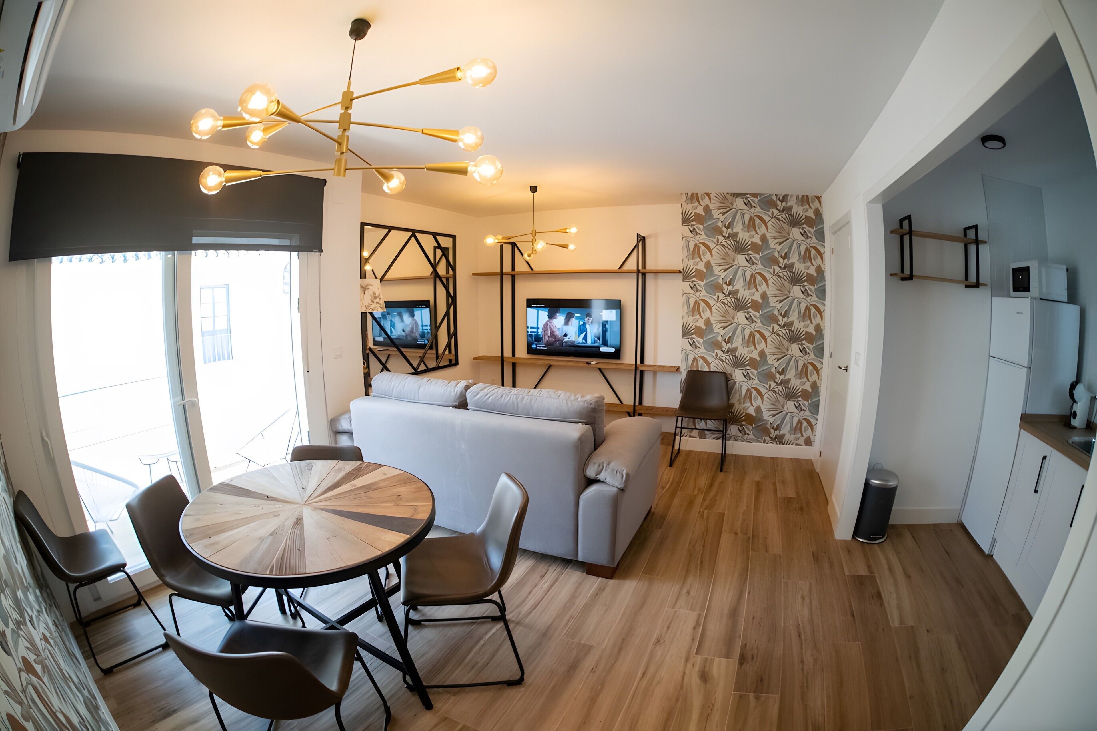 Een moderne woonkamer met een eethoek, een bank, een televisie en een keuken.