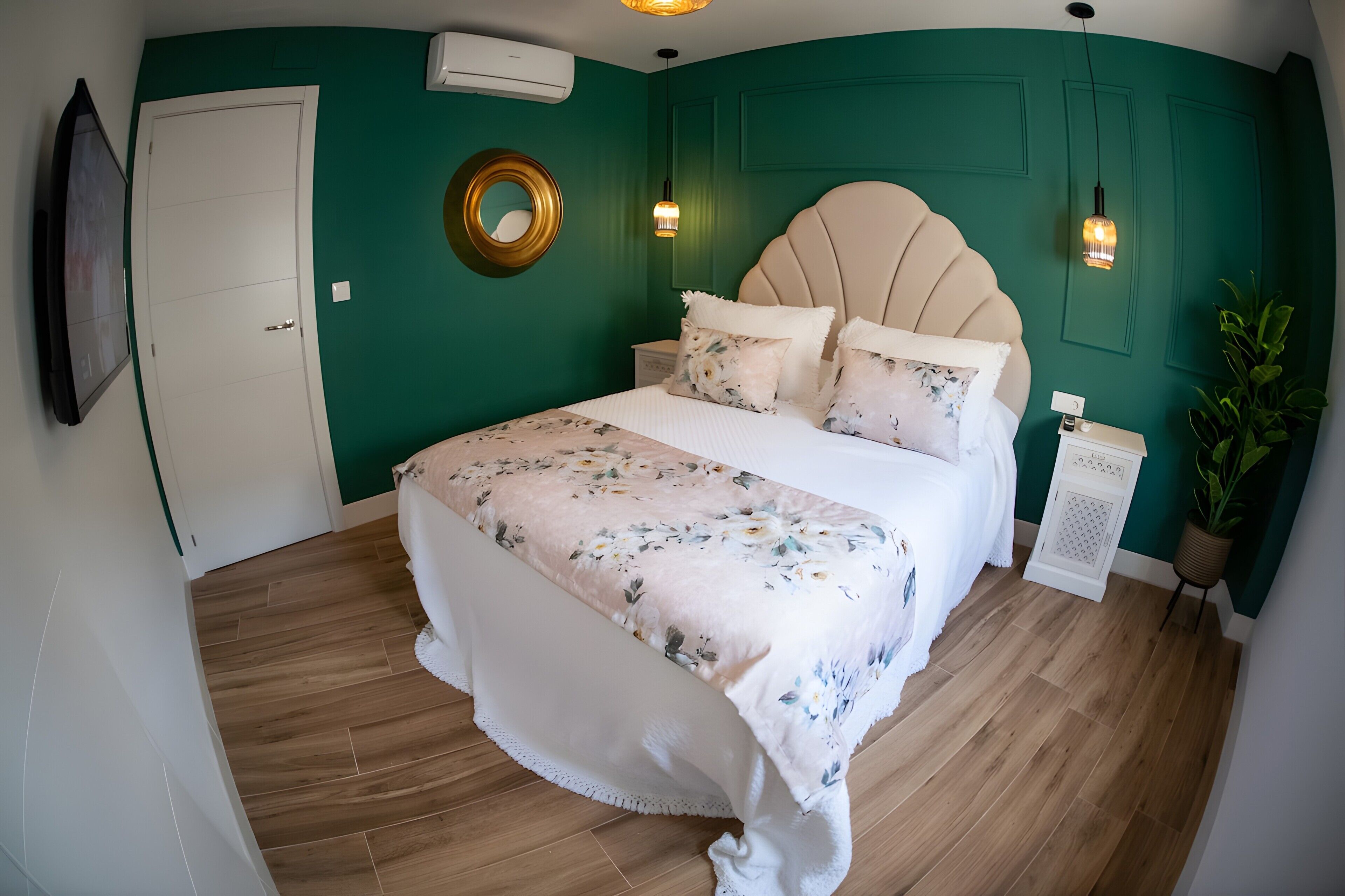 Un dormitorio con cama, mesita de noche, espejo y planta en maceta.