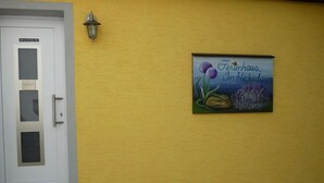 A yellow wall with a door and a sign that reads 'Ferienhaus Im Herkedain'. - Holiday home in Oberfell with swimming pool (Oberfell)