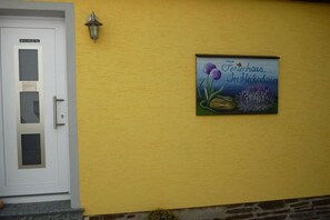 Eine gelbe Wand mit einer Tür und einem Schild, auf dem 'Ferienhaus Im Herkedain' steht.