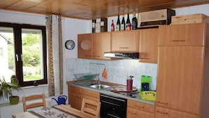 A compact kitchen with wooden cabinets, a built-in oven, and a window with a view of greenery. - Holiday home in Oberfell with swimming pool (Oberfell)