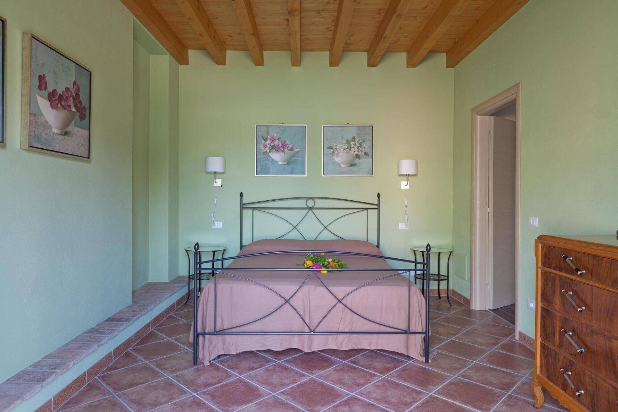 Une chambre à coucher avec un lit en métal, une commode en bois et deux lampes fixées au mur.