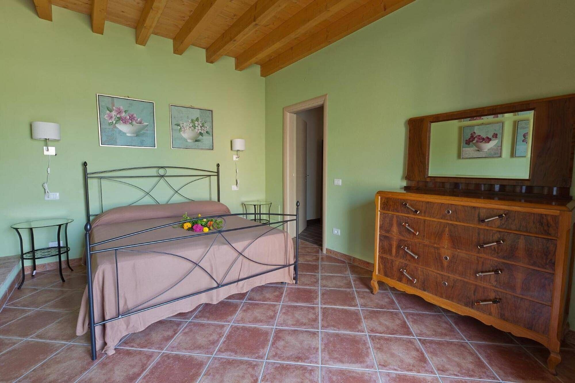 A bedroom with a bed, a dresser, and two wall-mounted lamps.