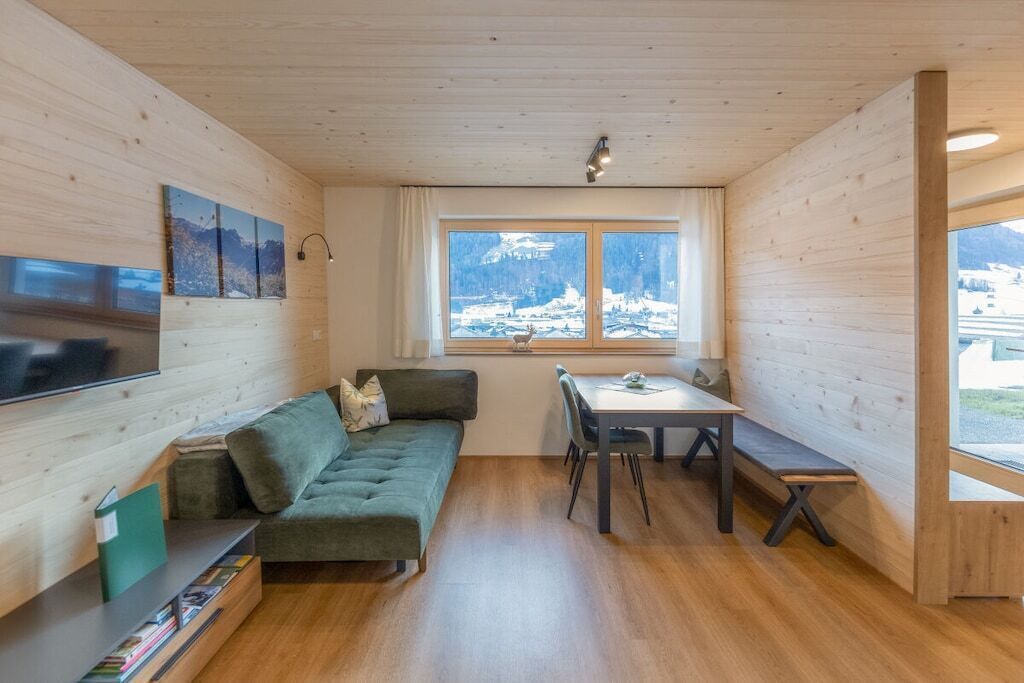 A cozy room with a sofa, a dining table, and a window with a view of mountains.