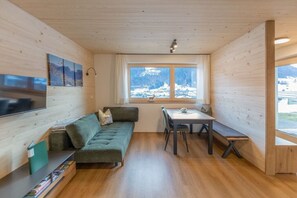 Une pièce confortable avec un canapé, une table à manger et une fenêtre donnant sur les montagnes.