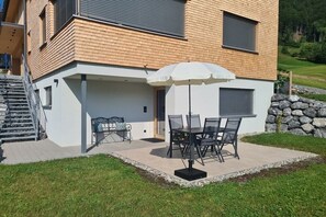 Una casa moderna con un patio, mobiliario exterior y una pared de piedra.