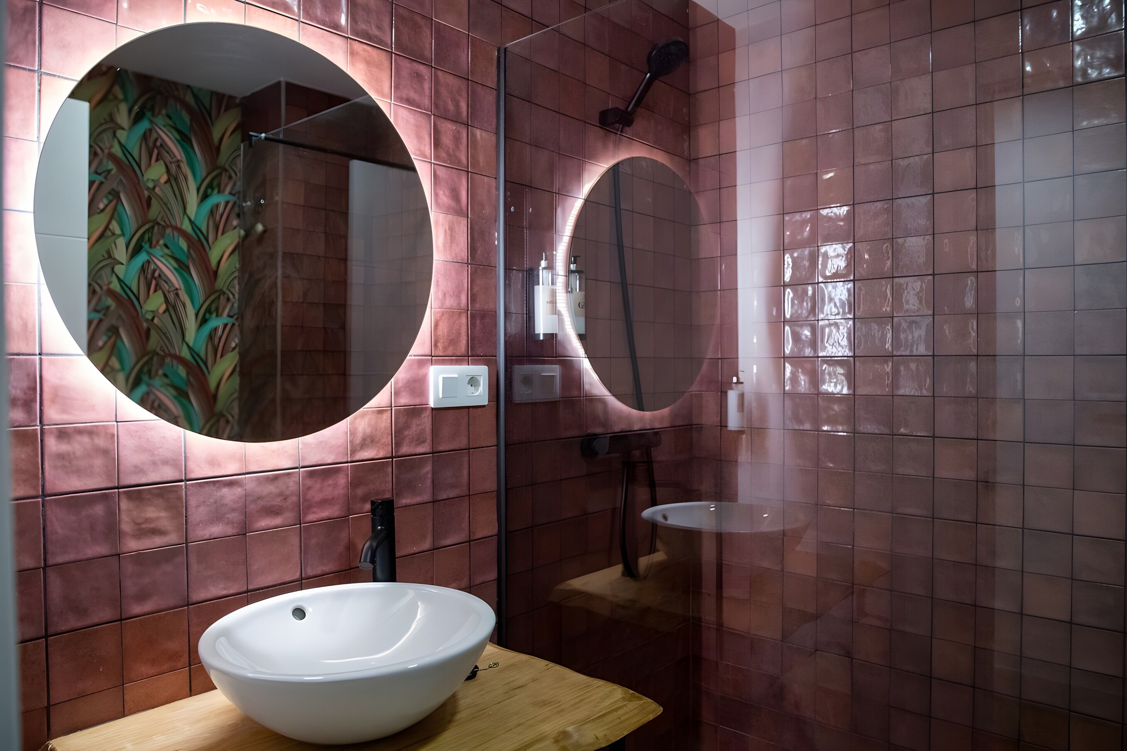 Ein Badezimmer mit rundem Spiegel, Waschbecken und Dusche.