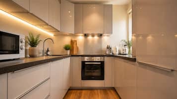 A modern kitchen with white cabinets, a built-in oven, and a microwave.