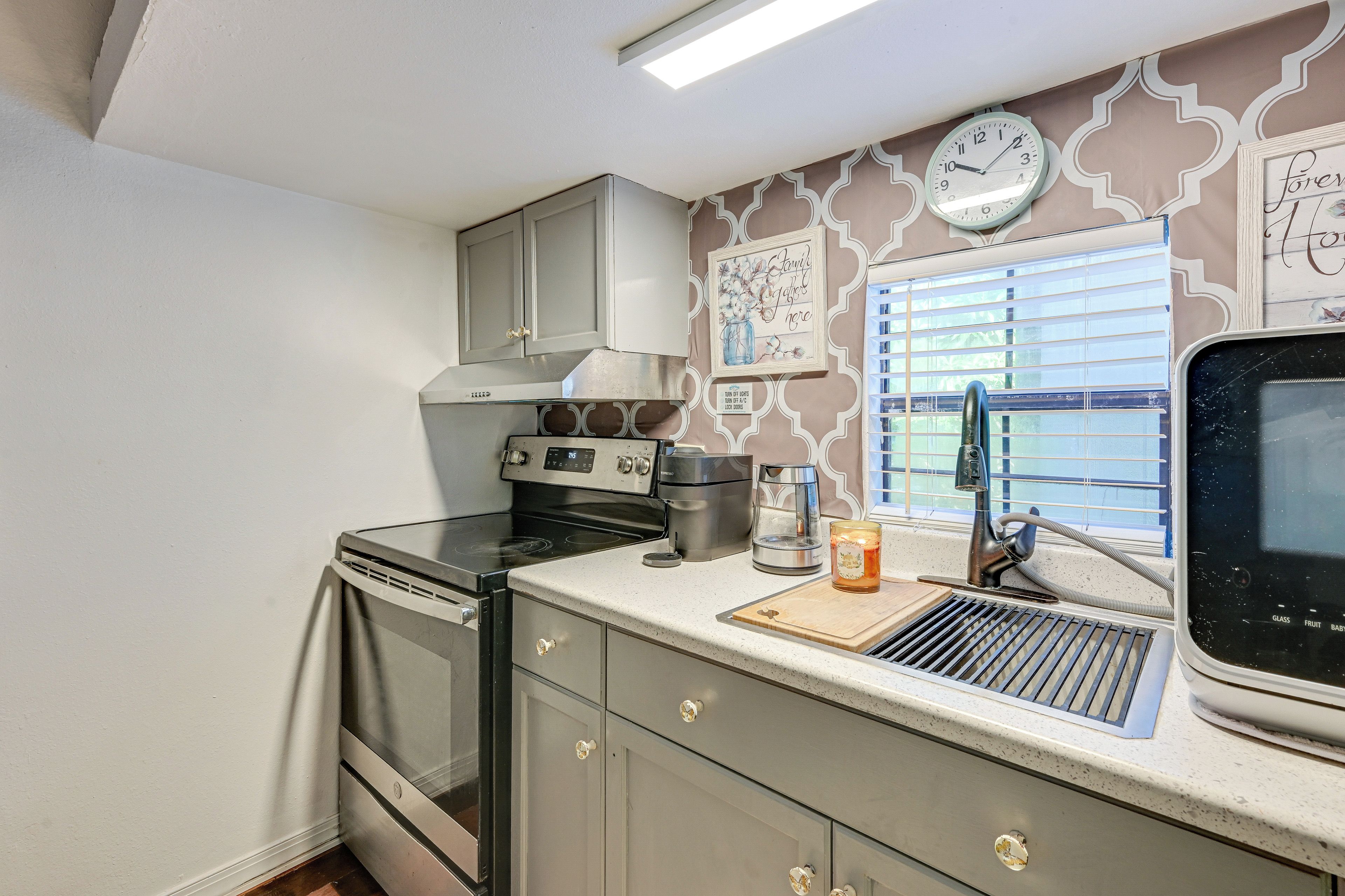 A kitchen with a stove, oven, and a window with blinds.