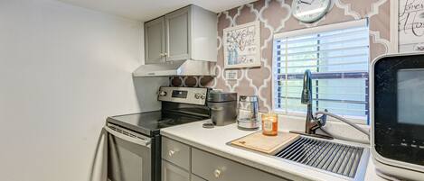 A kitchen with a stove, oven, and a window with blinds.