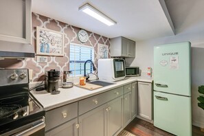 A kitchen with a vintage-style refrigerator, a coffee maker, and a microwave.