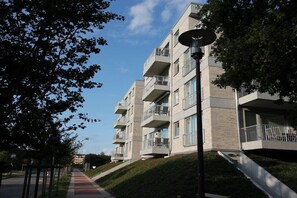 Ein mehrgeschossiges Wohngebäude mit Balkonen, einem Fußweg und einer Straßenlaterne.