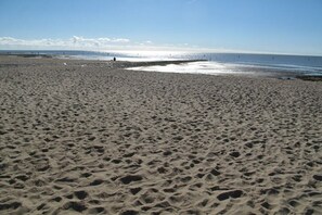 Ein Sandstrand mit Fußabdrücken, die zum Wasser führen.