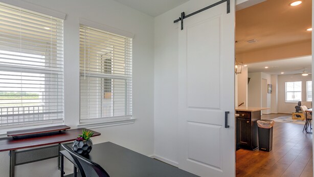 A modern interior with a sliding door leading to a dining area, a small table with a plant, and a bench.