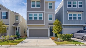 A multi-story residential building with a central garage, a driveway, and a car parked in the driveway.