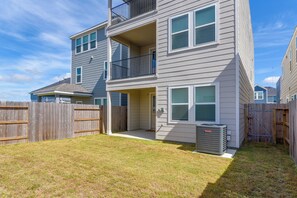 A two-story residential building with a balcony, a fenced yard, and a visible air conditioning unit.