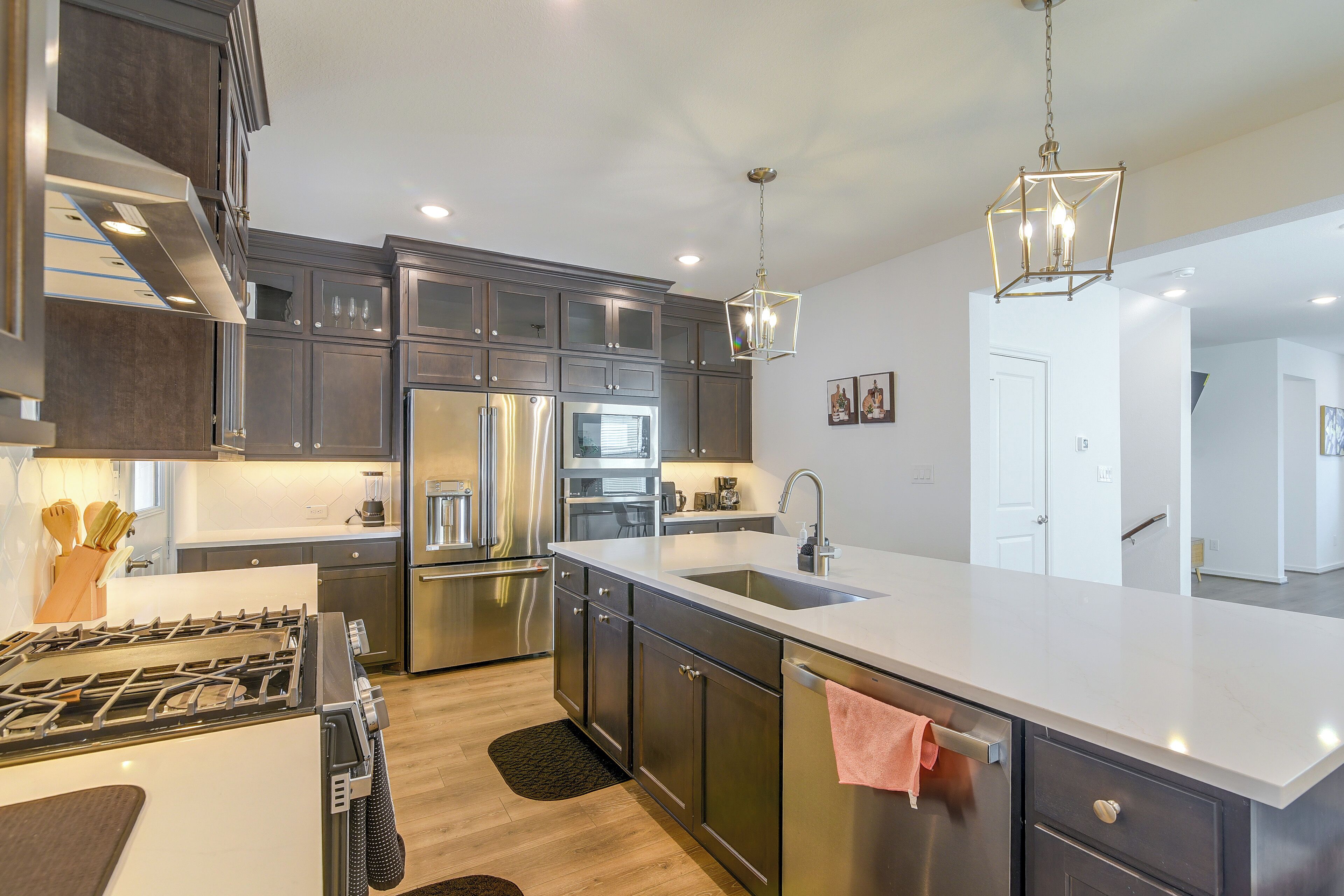 A modern kitchen with stainless steel appliances, a large island, and pendant lighting.