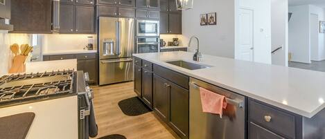 A modern kitchen with stainless steel appliances, a large island, and pendant lighting.