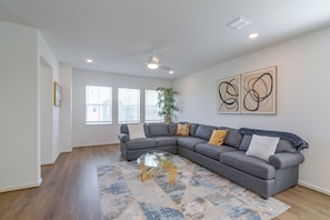 A modern living room with a grey sectional sofa, a glass coffee table, and a patterned rug.
