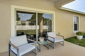 An outdoor patio with two chairs and a small table, a sliding glass door, and a potted plant. - Bright Cape Coral Home, 9 Mi to Downtown (Cape Coral)