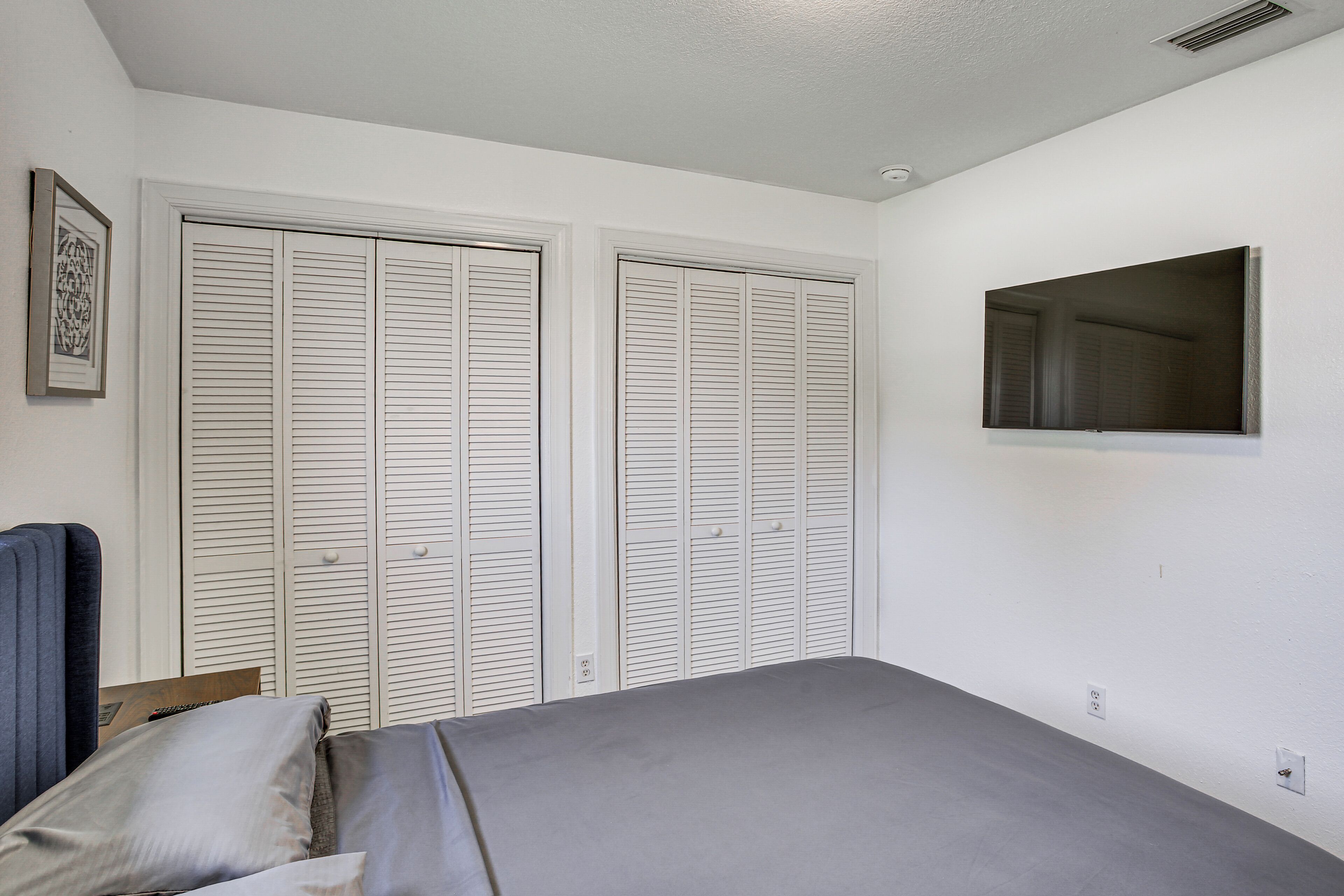 A bedroom with a bed, a wardrobe, a mirror, and a picture on the wall.