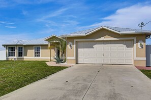 A residential house with a garage, a covered porch, and a well-maintained lawn. - Bright Cape Coral Home, 9 Mi to Downtown (Cape Coral)