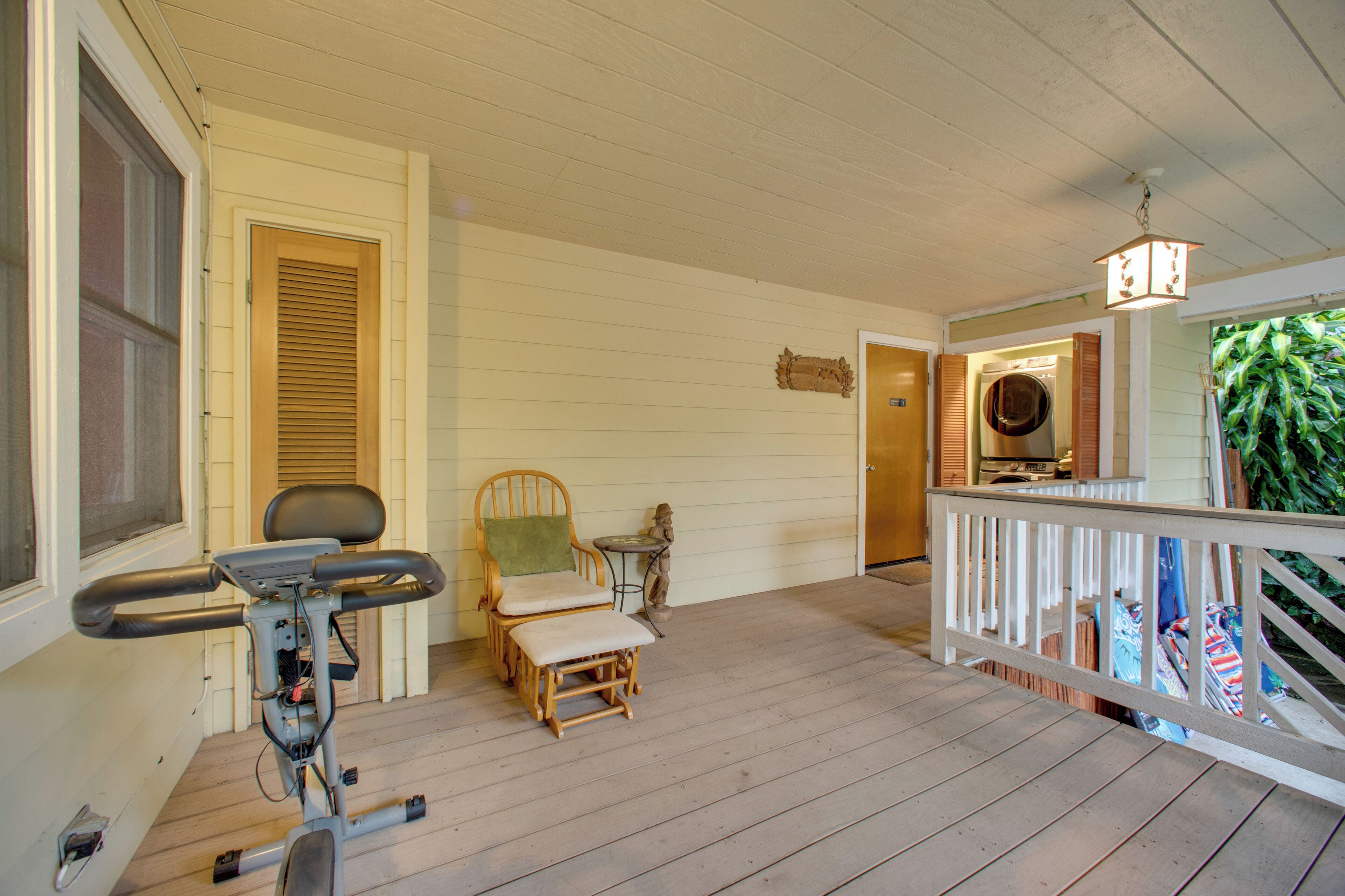 A wooden deck with exercise equipment, a chair, and a small table.