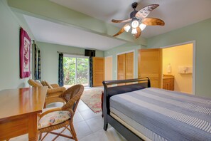 Quarto com cama, escrivaninha, cadeira e ventilador de teto.