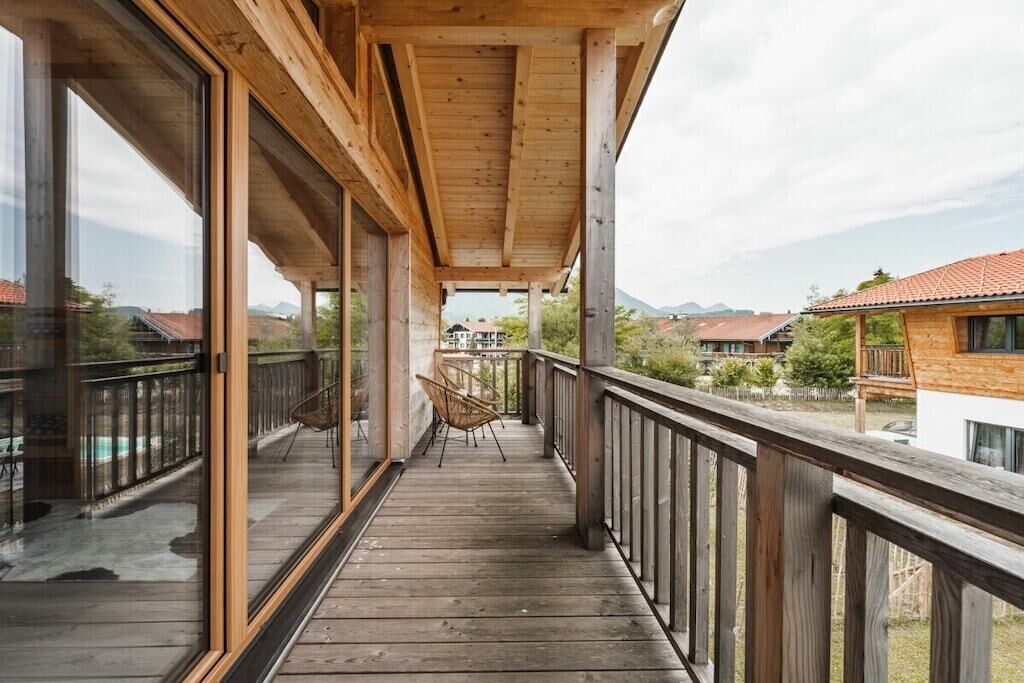 En træterrasse med gelænder, en stol og udsigt til huse i det fjerne.