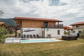 A residential building with a swimming pool, outdoor seating, and a hot tub.