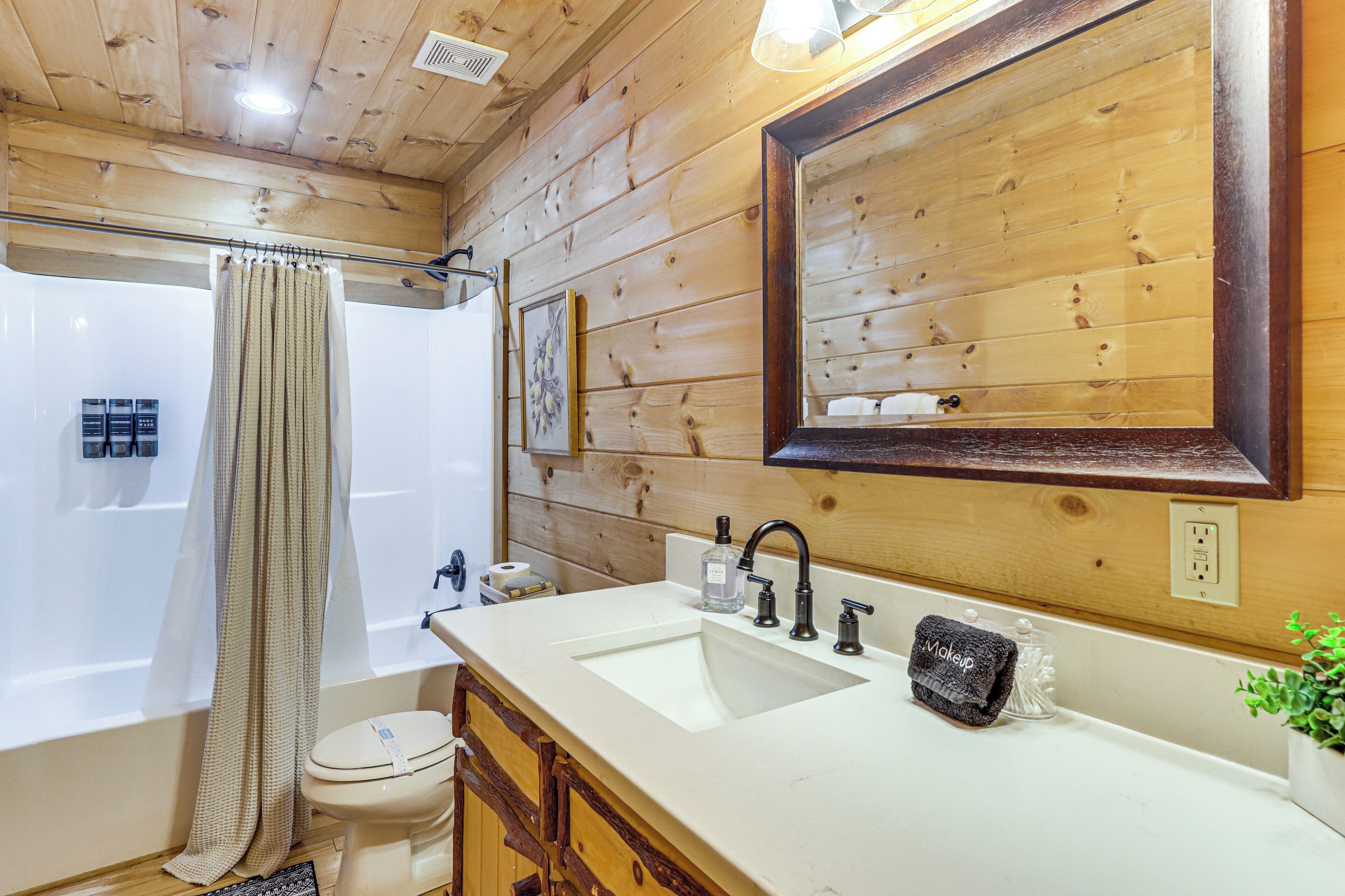 Un baño de madera con un espejo grande, un lavamanos y un inodoro.