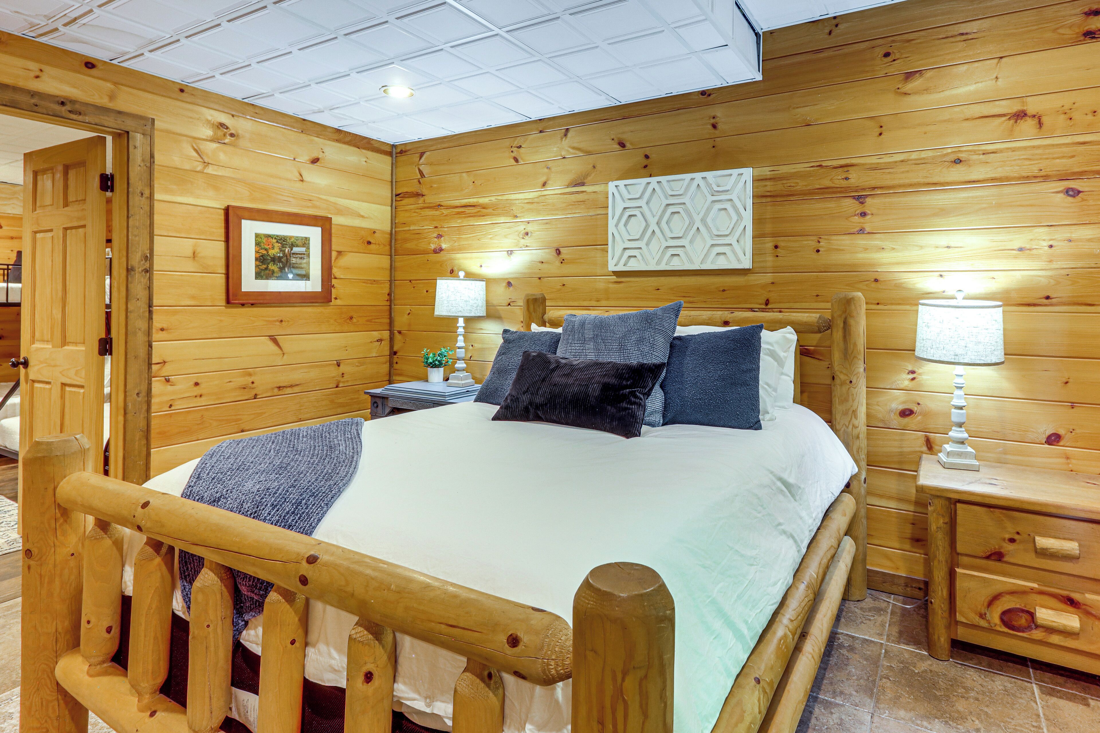 A wooden-paneled bedroom with a bed, bedside tables, and a nightstand.