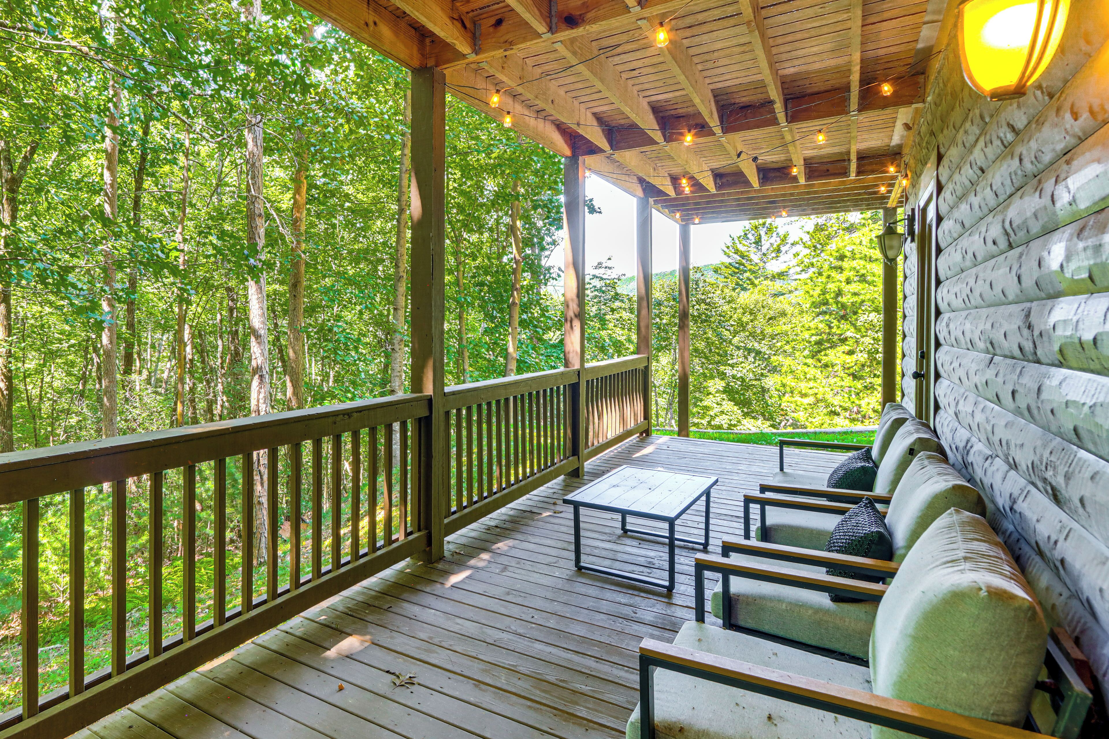 A wooden deck with a table and chairs, surrounded by trees.